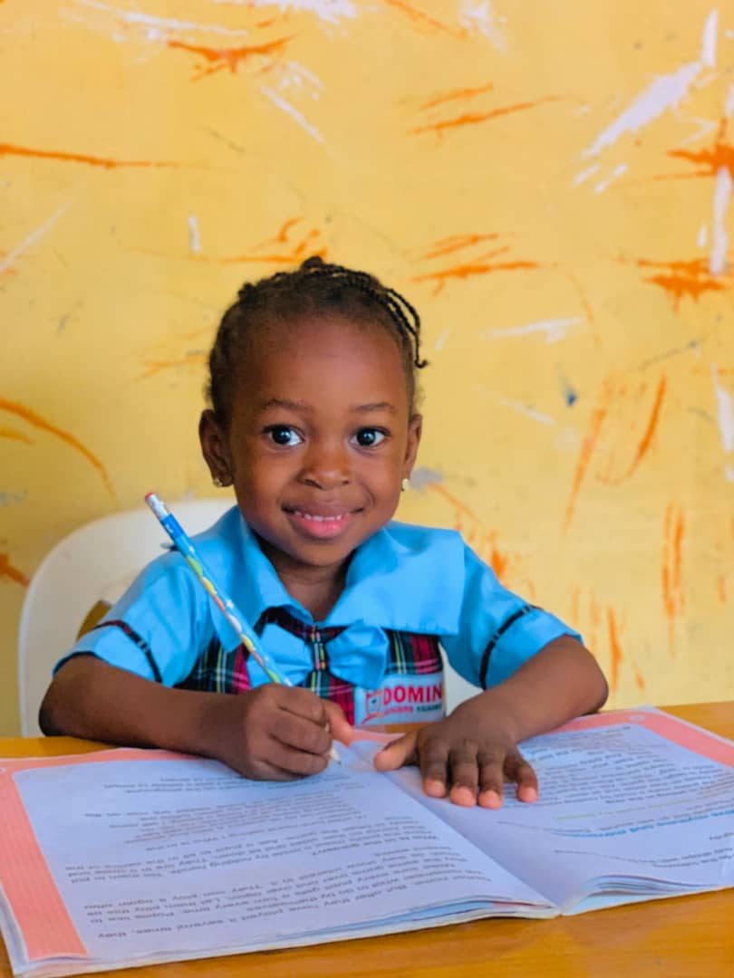Nursery pupil writing in her workbook